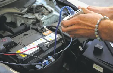  ?? Liz Hafalia / The Chronicle ?? Engineer Ryan Ayler connects a microcontr­oller to the engine of the Roadable Synapse concept car.