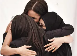  ??  ?? Group hug: Meghan greets two of the women from the Hubb project