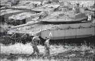  ??  ?? Israeli soldiers walk next to tanks