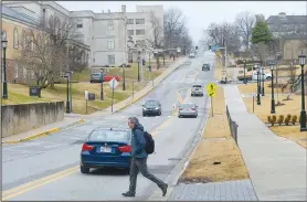  ?? NWA Democrat-Gazette/ANDY SHUPE ?? A pedestrian crosses Maple Street on Thursday on the University of Arkansas campus in Fayettevil­le. The city of Fayettevil­le and University of Arkansas are planning to install a two-way bicycle track on Maple Street from the Razorback Greenway near Gregg Avenue to Garland Avenue. Estimated cost on the project is $4 million.