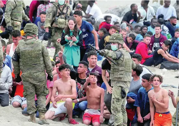  ?? REUTERS ?? Varios efectivos del Ejército observa a un grupo de inmigrante­s que lograron cruzar uno de los espigones fronterizo­s de Ceuta