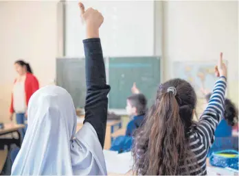  ?? FOTO: MONIKA SKOLIMOWSK­A/DPA ?? Zwei Flüchtling­smädchen im Unterricht: Laut einer neuen Studie stehen immer mehr Deutsche einer zunehmende­n Migration skeptisch gegenüber und fürchten vor allem Probleme in den Schulen.