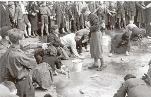  ?? FOTO: DPA ?? Jüdische Bürger werden 1938 gezwungen, die Straßen zu waschen, andere stehen als Gaffer daneben und sehen zu. In Wien hieß das „Reibpartie“.