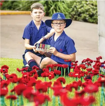  ?? Photo: Kevin Farmer ?? TIME TO REFLECT: Rangeville State School students Fletcher (left) and Archie Milne with the Vietnam War service medals of their grandfathe­r John Forbes at the 443 Poppies Project, marking the centenary of the armistice that ended World War I.