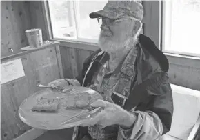  ?? PAUL A. SMITH / MILWAUKEE JOURNAL SENTINEL ?? Wayne Haag of Alagnak Lodge in Alaska offers freshly smoked salmon to guests.