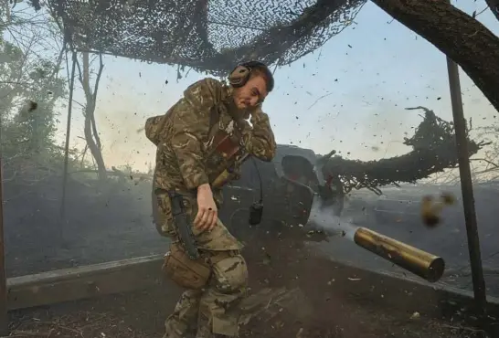  ?? LIBKOS ?? A Ukrainian soldier fires a cannon toward Russian positions July 5 near Bakhmut, a city in the Donetsk region of eastern Ukraine. Russia’s invasion of Ukraine has stretched past 21 months.