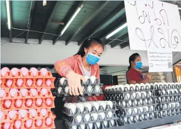  ?? SOMCHAI POOMLARD ?? An egg vendor in Samut Prakan’s Pak Nam market puts up a sign saying she has sold out of fresh eggs. People have been rushing to stockpile eggs after the government urged everyone to stay home during the outbreak.