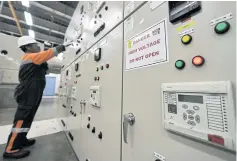  ??  ?? A technician checks a control panel.