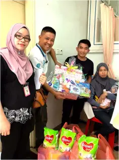  ??  ?? Wan hands over the hamper to Aznan and Norhayati, witnessed by Ediawati (left).