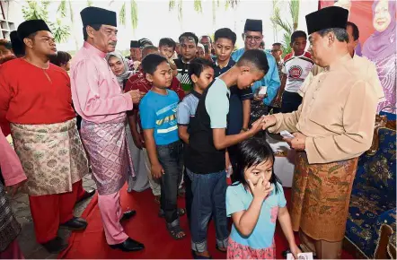  ??  ?? Season to share: Muhyiddin greeting and handing out ‘duit raya’ to children at the Pagoh Sports Complex.