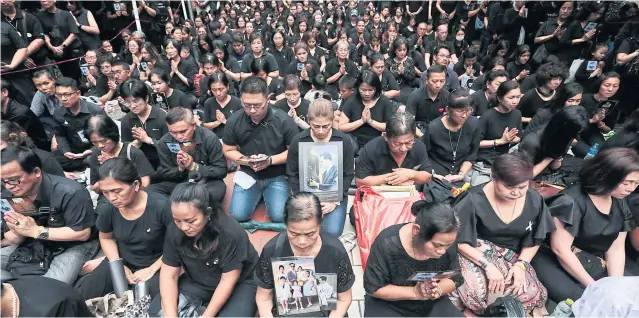  ?? PATIPAT JANTHONG ?? People mass at Siriraj Hospital and observe an extended period of silence at 3.52pm yesterday to commemorat­e the passing away there one year ago of the late King Bhumibol Adulyadej.
