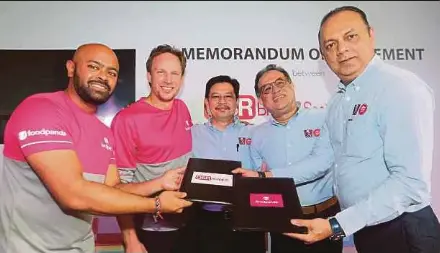  ?? PIC BY EIZAIRI SHAMSUDIN ?? foodpanda Malaysia managing director Sayantan Das (left) exchanging documents with QSR Brands (M) Holdings Sdn Bhd restaurant division chief executive officer (CEO) Merrill Pereyra at the signing ceremony in Petaling Jaya yesterday. With them are (from second left) foodpanda Asia Pacific CEO Jakob Angele, QSR Brands chairman Datuk Kamaruzzam­an Abu Kassim and its managing director Datuk Seri Mohamed Azahari Kamil.