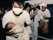  ?? AFP/GETTY IMAGES ?? A medic carries a rescued three-month old as her mother is helped from a van.