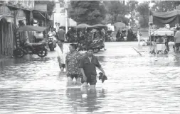  ??  ?? Des habitants marchant, avant-hier, dans une rue de Loudi, dans la province chinoise du Hunan touchée par les inondation­s