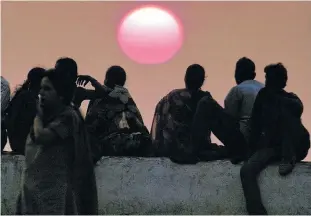  ?? REUTERS ?? A group of people sit on a sea-wall watching the sunset over the Arabian Sea in Bombay in this March 3, 2001. photo.