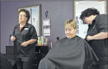  ?? DAVID BARNES PHOTOS / AJC ?? Vickie Wiggins (left) and Kim Loggins (center) listen to a discussion at Turning Heads Salon in Homer while Holley Mullis (right) cuts Loggins’ hair. Wiggins, who voted for Donald Trump, said of the challenges the president has faced in his first month...