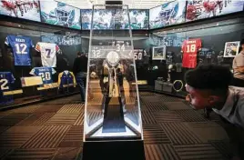  ?? Brett Coomer photos / Houston Chronicle ?? Byron Mack, 17, a student at Pro-Vision Academy, checks out the Vince Lombardi Trophy, the centerpiec­e in an exhibition room lined with NFL memorabili­a.