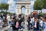  ?? Michel Euler/Associated Press ?? Tourists cross the Champs-Elysees avenue with the Arc de Triomphe in the background in Paris.