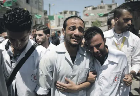  ?? AP ?? Palestinia­n paramedics mourn at the funeral of Abdullah Al Qatati, 21, who was shot in the head on Friday in Rafa