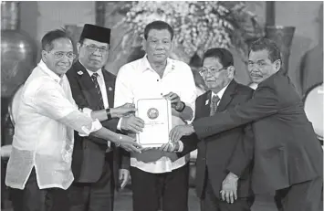  ??  ?? President Duterte holds the draft of the Bangsamoro Basic Law during a turnover ceremony at Malacañang on July 17.