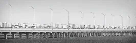  ?? Photos by Bob Owen / Staff photograph­er ?? A long line of trucks wait on the Pharr-Reynosa Internatio­nal Bridge to enter the United States as others make their way into Mexico.