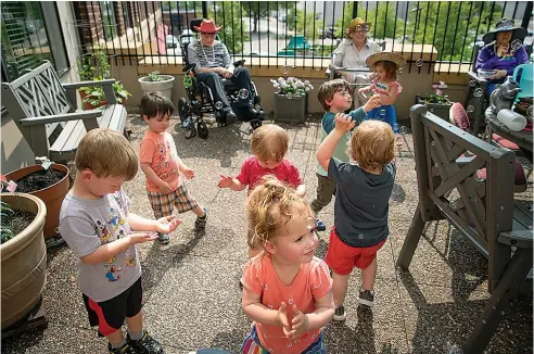  ?? Elizabeth Flores/ Minneapoli­s Star Tribune/TNS ?? ■ Children from the TowerLight Child Care Center play with bubbles as TowerLight Memory Care Unit residents watched after they watered plants as part of their multigener­ational program May 31 in St. Louis Park, Minn.