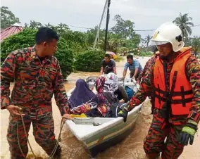  ??  ?? Off to safety: Fire and Rescue Department personnel escorting residents out of their homes at Kampung Pulai, Gelang Patah.