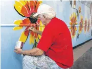  ??  ?? Bob Palmer, owner of Palmer Studios and the Red Dirt Gallery, paints an Indian blanket on his mural at the Plaza Mayor at the Crossroads.