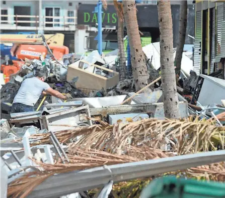  ?? JAY REEVES/AP ?? A man hauls debris away from a pizza restaurant that was destroyed by Hurricane Ian at Fort Myers Beach on Sunday.