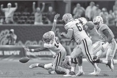  ?? STAFF PHOTO BY C.B. SCHMELTER ?? Tennessee linebacker Daniel Bituli, rear, forces Georgia Tech quarterbac­k TaQuon Marshall, left, to fumble during Monday night’s Chick-fil-A Kickoff Game at Mercedes-Benz Stadium in Atlanta. Marshall ran for 249 yards and scored five touchdowns, while...