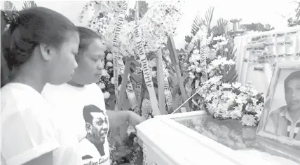  ?? PHOTO BY RAFFY T. CABRISTANT­E ?? Lourdes Sestoso, with her daughter Eden, 13, looks over the casket of her slain husband Edmund Sestoso.
