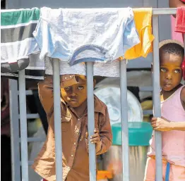  ?? AP ?? Children look through a fence at a shelter for families displaced by gang violence, in Port-au-Prince, Haiti.