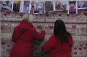  ?? ALASTAIR GRANT — THE ASSOCIATED PRESS FILE ?? Family members write a message to two sisters who died of COVID at the National Covid Memorial wall in London.