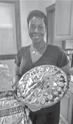  ??  ?? A slimmed-down Bridgett Wilder holds a fruit pizza created by fellow dietitian Angie Wilkes Tate at one of her nutrition classes.