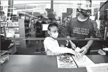  ?? STACEY WESCOTT/CHICAGO TRIBUNE ?? Charolette Baker, 7, and her uncle, William Hawkins, buy books May 29 at Anderson Bookshop in Naperville.