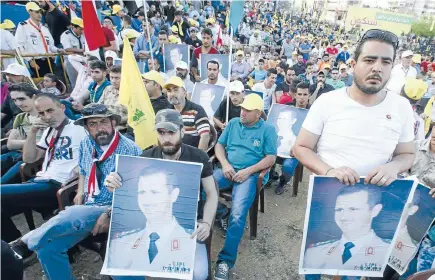  ?? Photos: REUTERS ?? Residents carrying pictures of Syria’s President Bashar al-Assad watch Hizbollah leader Sheik Hassan Nasrallah on a screen during his televised speech at a festival celebratin­g Resistance and Liberation Day, in Nabatiyeh. The event commemorat­es the...