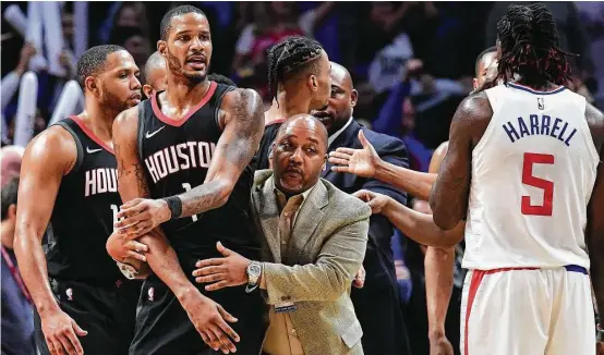  ?? Harry How / Getty Images ?? Not exactly seeing eye to eye with L.A.’s Montrezl Harrell, the Rockets’ Trevor Ariza (1) is restrained by Bryant Savage of team security before his ejection Monday.