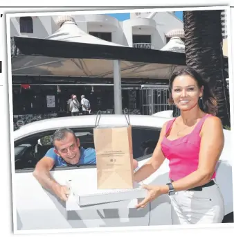  ?? Picture: GLENN HAMPSON ?? Customer Darren Graham makes the most of the ‘drive through’ takeaway offer from Surfers Italian favourite Costa D'Oro and restaurant owner Nuccia Fusco