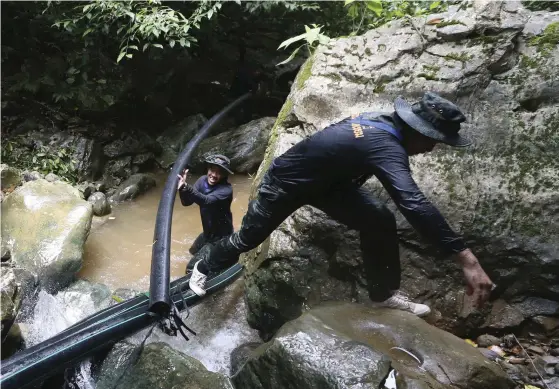  ?? FOTO: TT/AP/SAKCHAI LALIT ?? Thailändsk­a soldater kopplar ihop slangar som ska leda bort vattnet från grottorna där pojkarna sitter instängda.