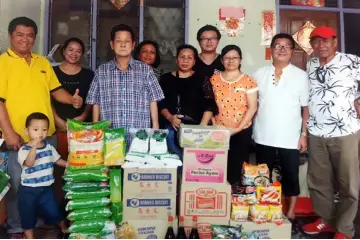  ??  ?? Lim (third left) hands over the items to James (right), who is tasked with distributi­ng them to the recipients.