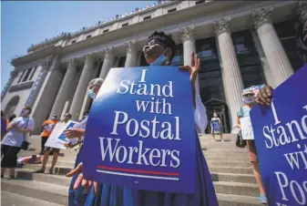  ?? Mark Lennihan / Associated Press ?? Protesters demonstrat­e against cutbacks in August in New York. The U. S. Postal Service agreed to reverse changes that slowed service, settling a lawsuit filed by Montana Gov. Steve Bullock.