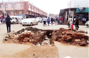  ?? ?? People walk past uncovered trench at corner Bank Street and Chinhoyi Street near Gulf Complex in Harare yesterday