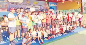  ?? ?? Tan (red shirt, standing centre) is flanked by Silvester (left, centre) and Koh (right, centre) with all the winners of Sabah junior tennis tournament first leg in Sandakan over the weekend.