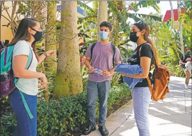  ??  ?? Palm Beach Atlantic University students chat between classes as they walk on campus. Schwinn said they had to decide last summer whether to open campus or stick solely with online learning.