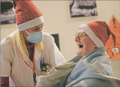  ?? (AP/Luca Bruno) ?? Celestina Comotti, 81, is comforted by director Maria Giulia Madaschi as she cries while talking on a video call with Alessia Mondello, a donor unrelated to her. Mondello bought and sent her a shawl as a Christmas present at the Martino Zanchi nursing home in Alzano Lombardo, Italy.