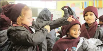  ?? Tracey Adams African News Agency (ANA) ?? The SA National Zakáh Fund delivered winter packs, food and treats to pupils of Morgenster Primary School in Hanover Park as part of the Sanzaf Operation Winter Warmth campaign. Grade R pupil Aaiesha Sellars, 5, struggles to get her arm into her jacket which is one of the items in the pack. Fawaaz Bester, 6, and Sameer Petersen, 6, try on the new clothing they received in their packs.