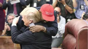  ?? OLIVER CONTRERAS/POOL/GETTY IMAGES ?? President Donald Trump hugs rapper Kanye West during a meeting in the Oval Office on Thursday. At the meeting, West advocated for imprisoned gang leader Larry Hoover.