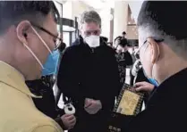  ??  ?? Zhang Xiaosong (right), executive vice president of SPAFFC, and the consuls general of Italy (center) and South Korea check the gifts and a letter for quarantine­d expats. — Ti Gong