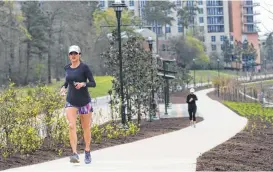  ?? Staff photo by Jason Fochtman ?? The Woodlands was ranked the 7th best city to live in the United States. Here, a woman runs through part of the The Woodlands Waterway, an 18-year project combining commercial and residentia­l centers with a 1.8 mile transit and pedestrian corridor...