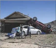  ?? AP PHOTO/ALONZO ADAMS ?? Neighbors walk in front of a home damaged at Wheatland Drive and Conway Drive on Monday, Norman, Okla.